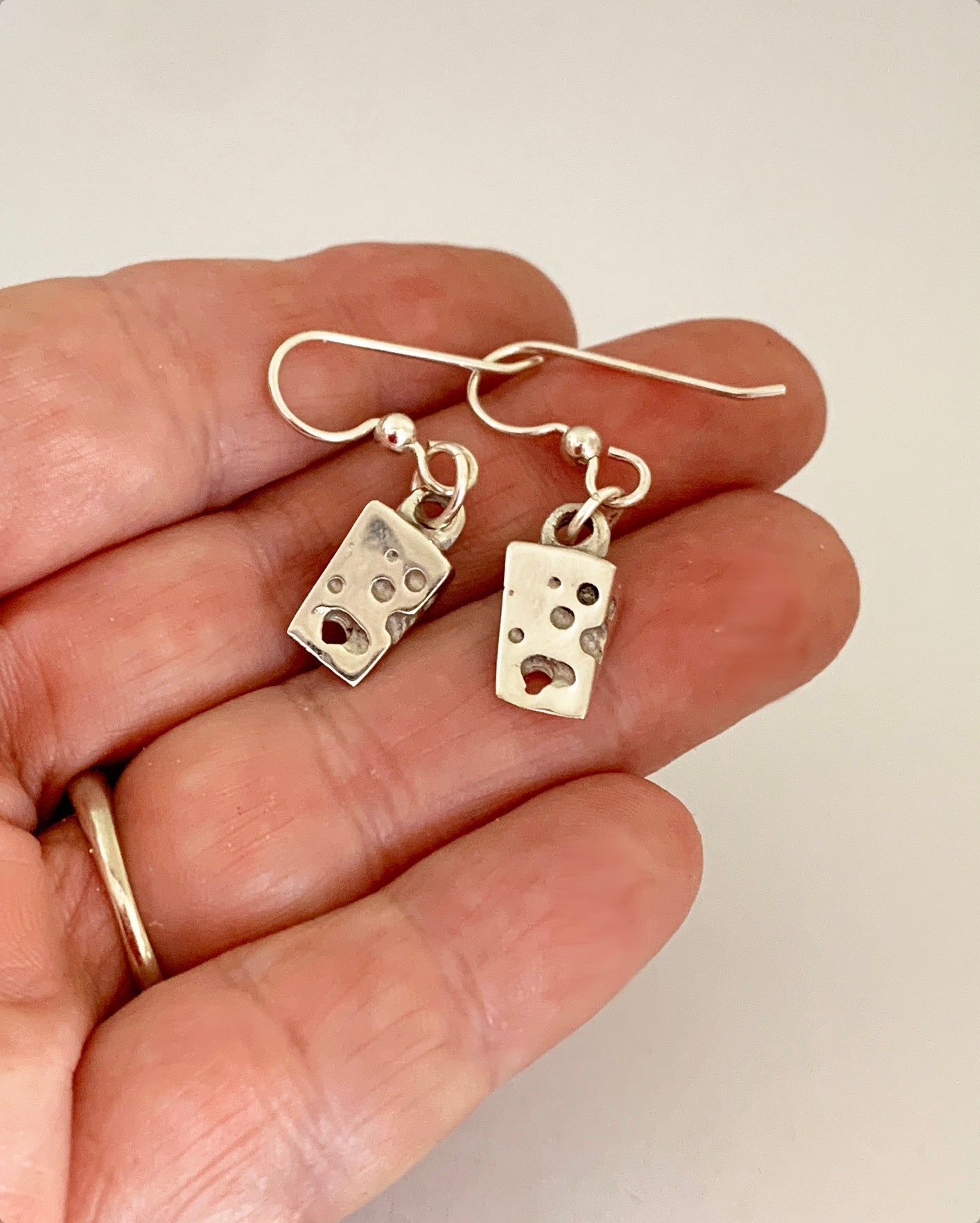 cheese earrings held by hand